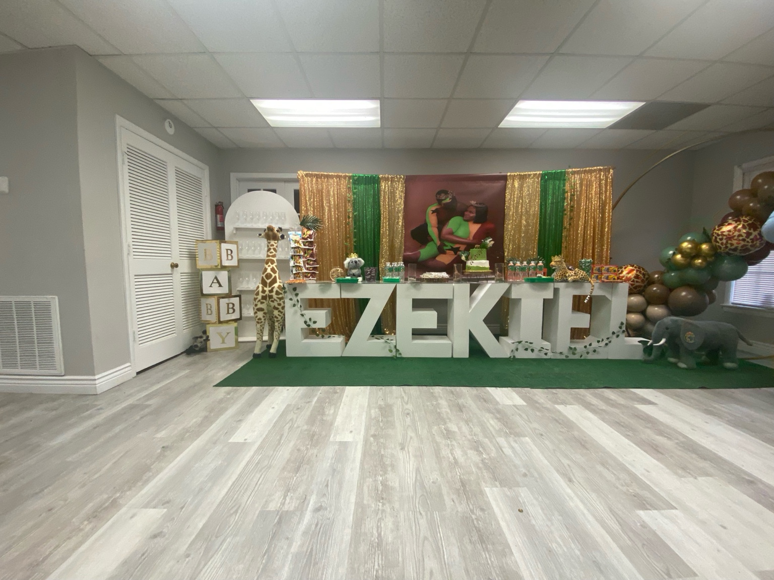 Personalized baby shower backdrop with green and gold decorations